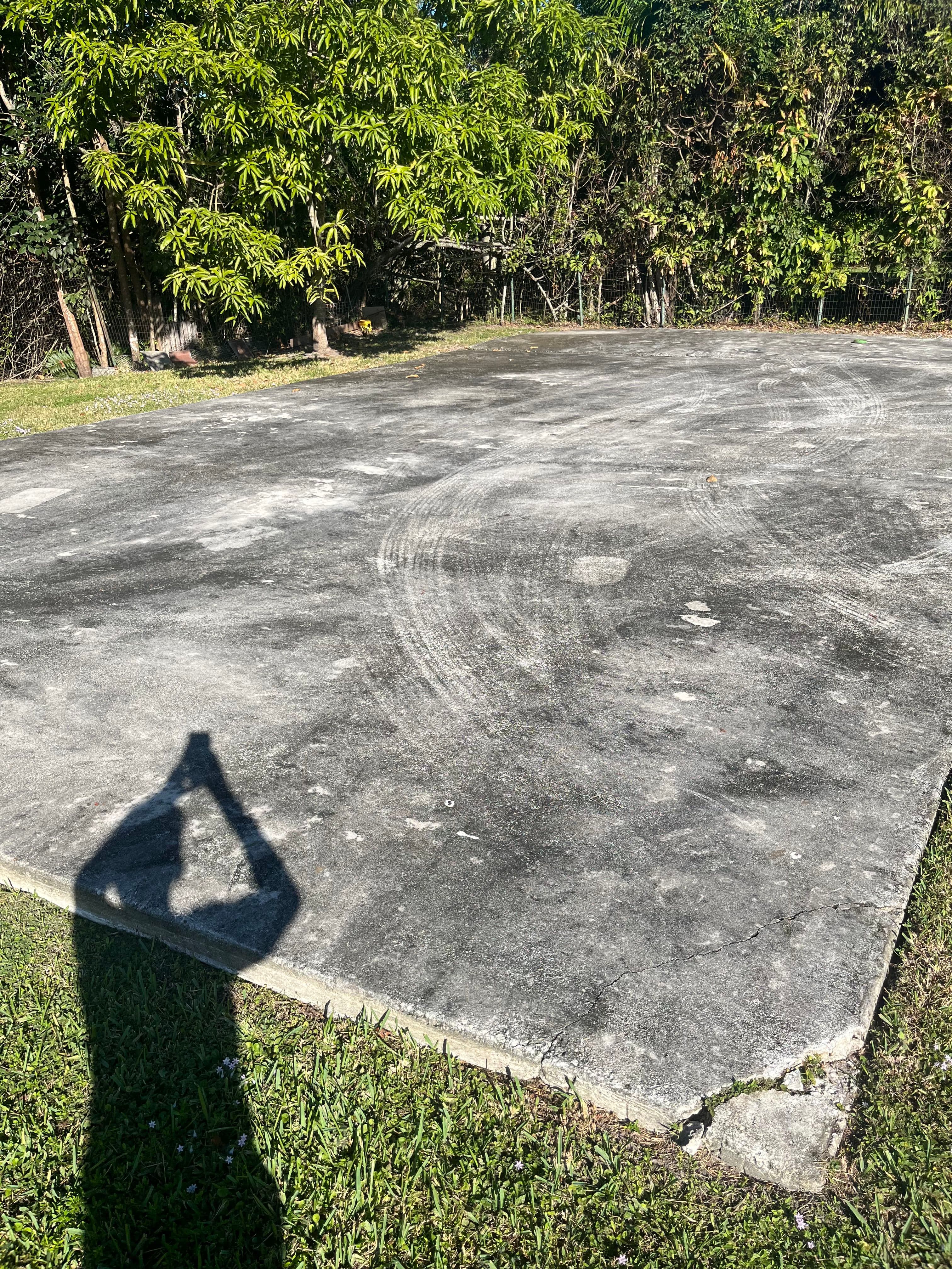 Concrete slab in a grassy area surrounded by trees, with a shadow of a person taking a photo.
